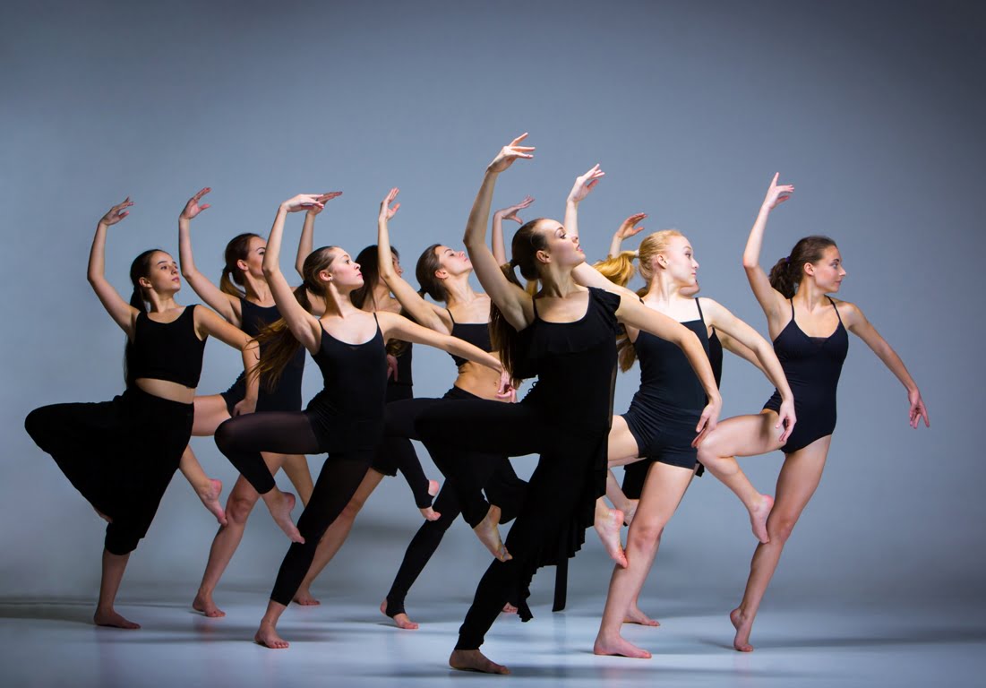 The group of modern ballet dancers dancing on gray background